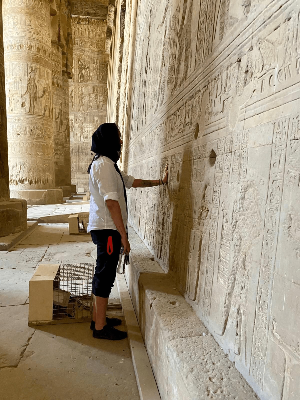 Mel Cobian with her hand on the carved wall of an Egyptian temple