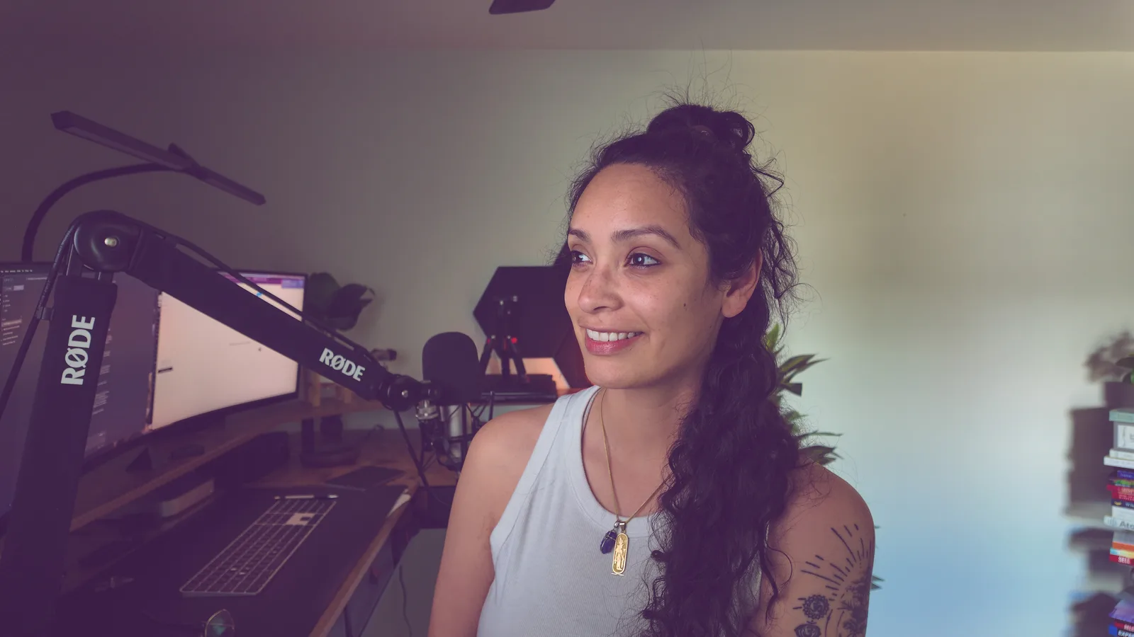 Mel Cobian smiling at her desk beside a broadcast microphone and a curved monitor