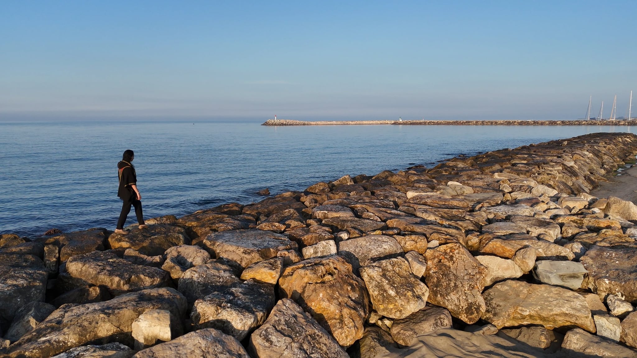 Mel Cobian walking along a rocky shoreline